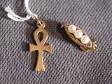 a gold cross and an ankht on a gray surface