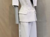 un mannequin vêtu d'un costume blanc orné de passementeries noires