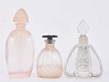 trois flacons de parfum posés l'un à côté de l'autre sur une surface blanche