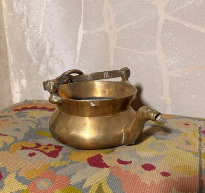 un petit pot en laiton posé sur un coussin