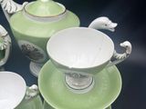 several pieces of green and white porcelain tea set on a table