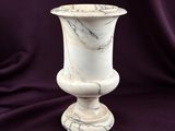 marble vase sitting on a purple cloth with a purple background
