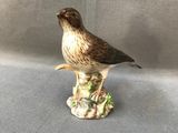 une petite figurine représentant un oiseau perché sur un morceau de bois