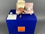 a figurine of a cat sitting on a couch with a blanket