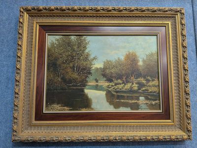une peinture à l'huile représentant une rivière, dans un cadre doré, accrochée à un mur bleu