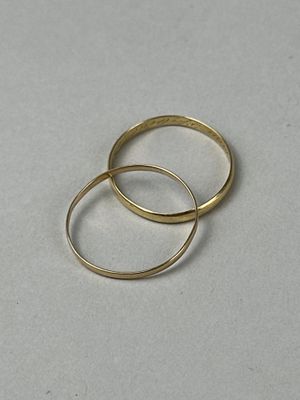 two gold rings sitting on top of each other on a white surface