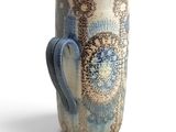 a blue and white vase with a handle on a white surface