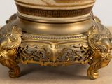 a gold vase with a picture on it on a table