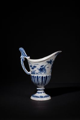 a blue and white porcelain pitcher with a handle on a black background