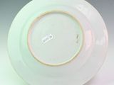 a white plate with a gold rim on a stand