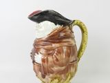 a brown and white pitcher with a black bird on top of it