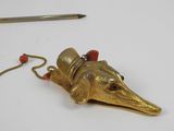 brass figurine of a bird with a hat and a pencil on a white surface