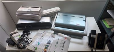 un bureau sur lequel se trouvent un ordinateur portable, une imprimante et d'autres appareils électroniques