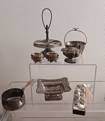 une vitrine en verre sur laquelle sont exposés des objets en argent