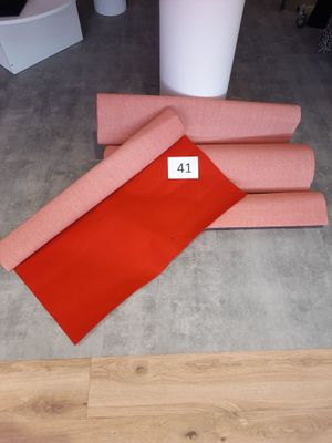 trois rouleaux de tissu rouge posés sur un parquet