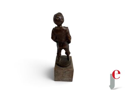 une petite statue représentant un garçon debout sur un bloc