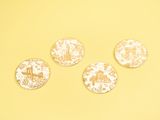 four gold and white coasters on a yellow background