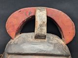 a wooden mask with a red handle on a black background