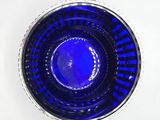 a blue glass bowl sitting on a white surface