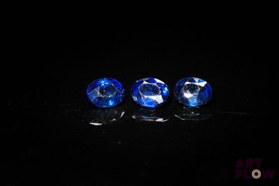 trois saphirs bleus posés sur une surface noire