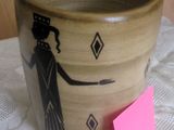un vase marron orné d'un motif noir, posé sur une table