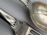 two silver spoons and a fork on a table
