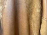 the back of a brown leather jacket hanging on a hanger