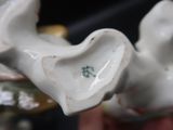 une figurine en porcelaine blanche représentant un oiseau sur lequel repose une feuille verte
