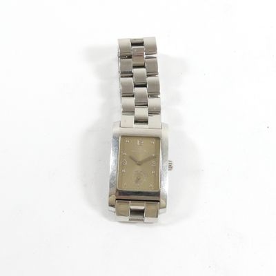 une montre en argent posée sur une surface blanche