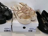 trois paires de chaussures noires et dorées sont posées sur une boîte blanche