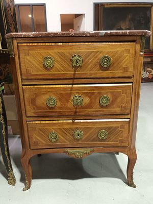 a small chest of drawers in a room with pictures on the wall