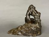 a bronze statue of a man sitting on a rock