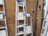 Plusieurs échelles sont empilées contre un mur dans une pièce.