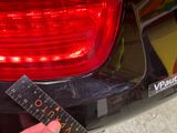 a person holding a ruler in front of a car