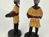 two figurines of a man and a woman in yellow dresses