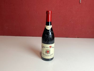 une bouteille de vin posée sur une table, avec un mur rouge en arrière-plan