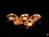 three orange sapphires sitting on top of a black surface