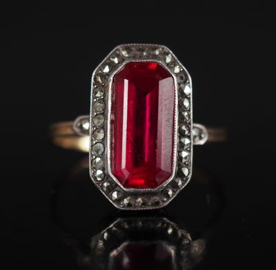 a close up of a red stone ring on a black surface