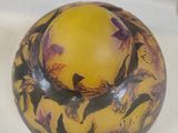 a yellow vase with birds on it sitting on a table