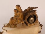 a statue of a woman sitting on a bench next to a clock