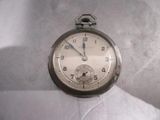 une montre de poche en argent posée sur une surface blanche