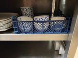 many plates and bowls in a blue basket on the shelf