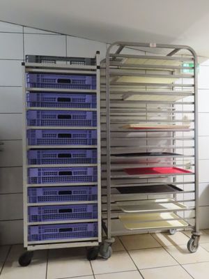 Plusieurs plateaux de nourriture sont empilés sur un chariot dans une cuisine