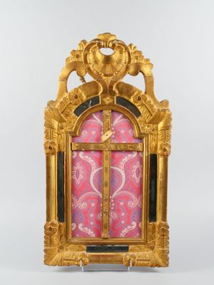 une image représentant une horloge dorée sur fond rose, ornée de motifs dorés