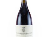 the bottle of red wine is sitting on a white surface