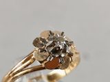 a gold ring with a diamond in it on a clear surface