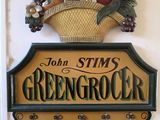 une enseigne indiquant « John Stim, primeur », avec un panier de fruits accroché au mur