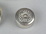 two silver buttons that are sitting on a white surface