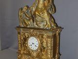 a gold clock with a statue on top of it