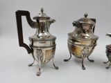 three silverplated teapots and a coffee pot on stands